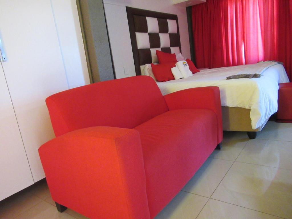 a bedroom with a red chair and a bed at Jericho Hotel and Conferences in Thohoyandou