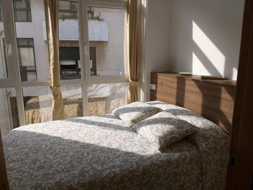 a bed with pillows in a bedroom with a window at Apartamento en Ribeira(centro) 3* planta in Ribeira