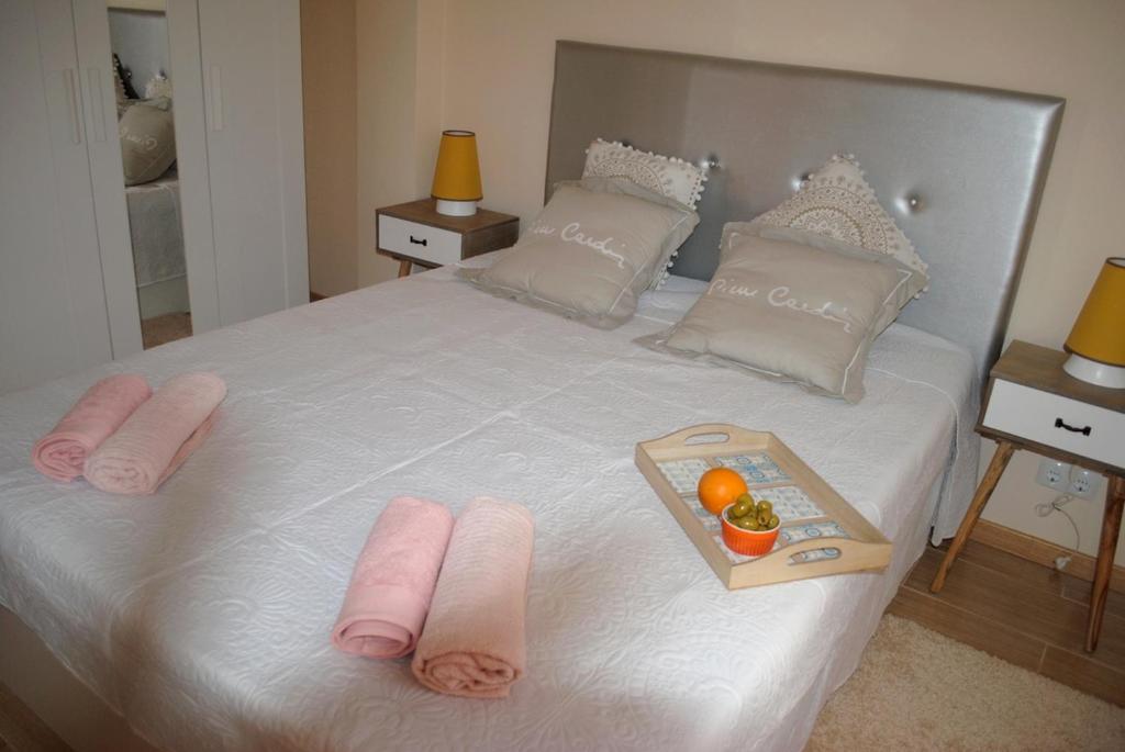a white bed with pink towels and fruit on it at Aparatamento Barraques Gandia Playa para 3-4 personas 150 metros de la playa in Gandía
