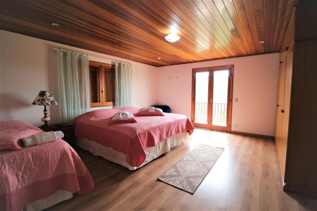 1 dormitorio con 2 camas y techo de madera en Recanto Cantinho do Céu, en Campos do Jordão
