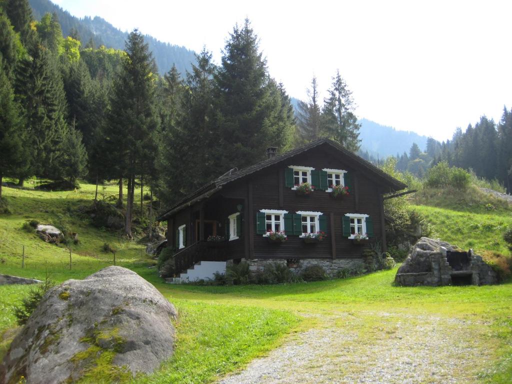 a small house in a field with a rock at Ferienhaus Schnetzer in Sankt Gallenkirch