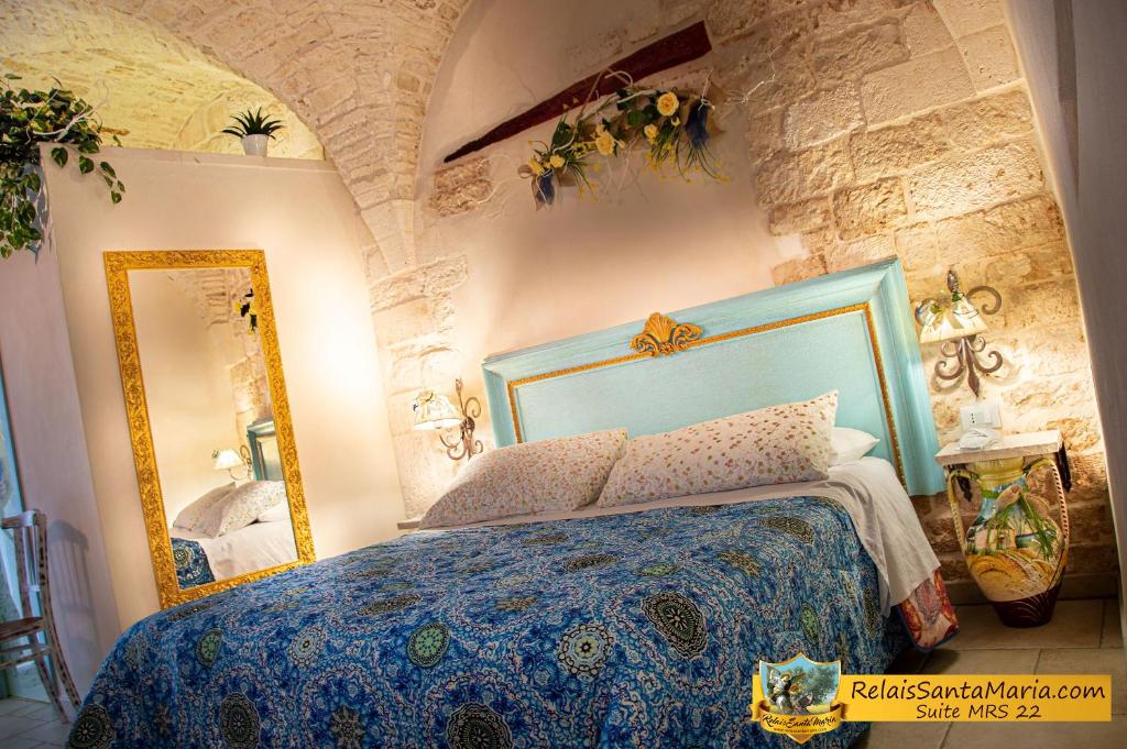 a bedroom with a blue bed and a mirror at Relais Santa Maria in Martina Franca