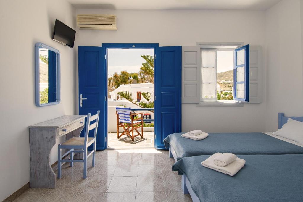 a room with two beds and a desk and a table at Evgenia Rooms and Apartments in Chora Folegandros