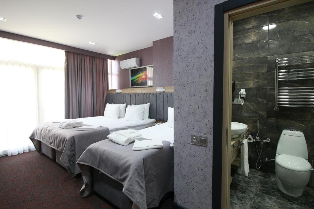 Home Suites Baku-Halal Hotel في باكو: غرفة فندقية بسريرين ومغسلة