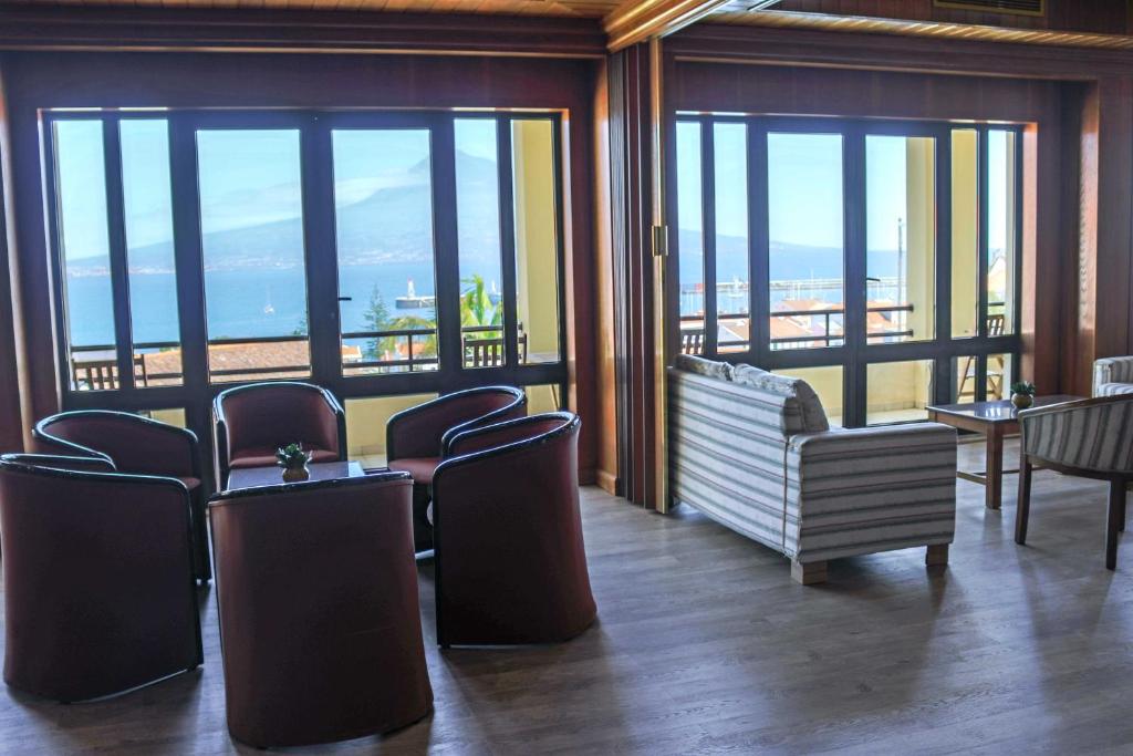 a room with chairs and a couch and windows at Hotel Horta in Horta