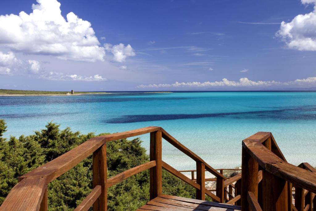 a view of the ocean from a wooden balcony at Casa La Pelosa in Stintino