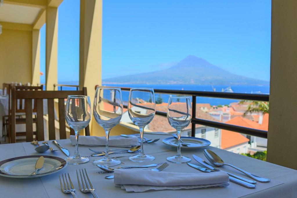 a table with wine glasses and a view of the ocean at Hotel Horta in Horta