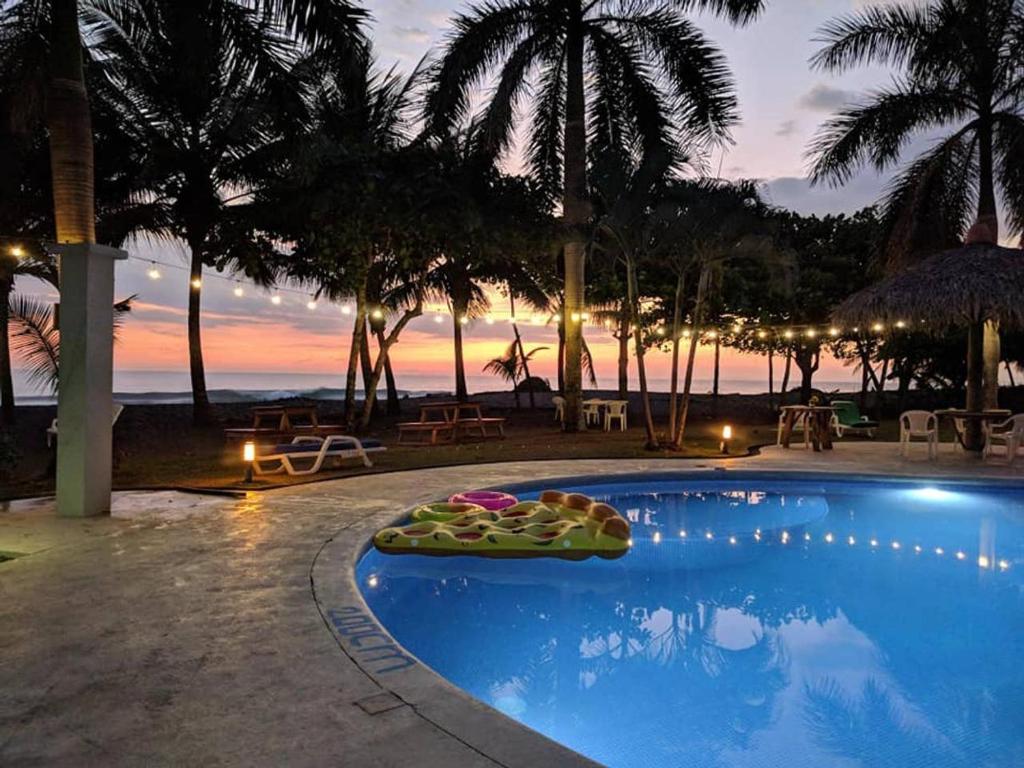 a swimming pool with a view of the ocean at night at Hermosa Beach House in Playa Hermosa