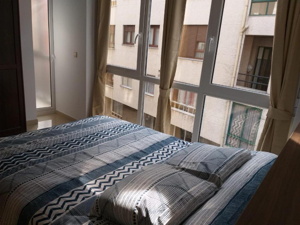 a bedroom with a bed and a large window at Apartamento en Ribeira(centro) 2* planta in Ribeira