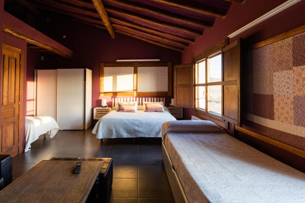 1 Schlafzimmer mit 2 Betten, einem Tisch und Fenstern in der Unterkunft La Casa Azul in Alcanadre