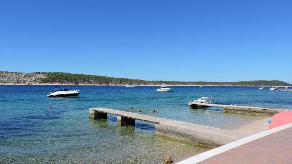 a beach with boats and people in the water at Vila Paula 6+1 in Rab