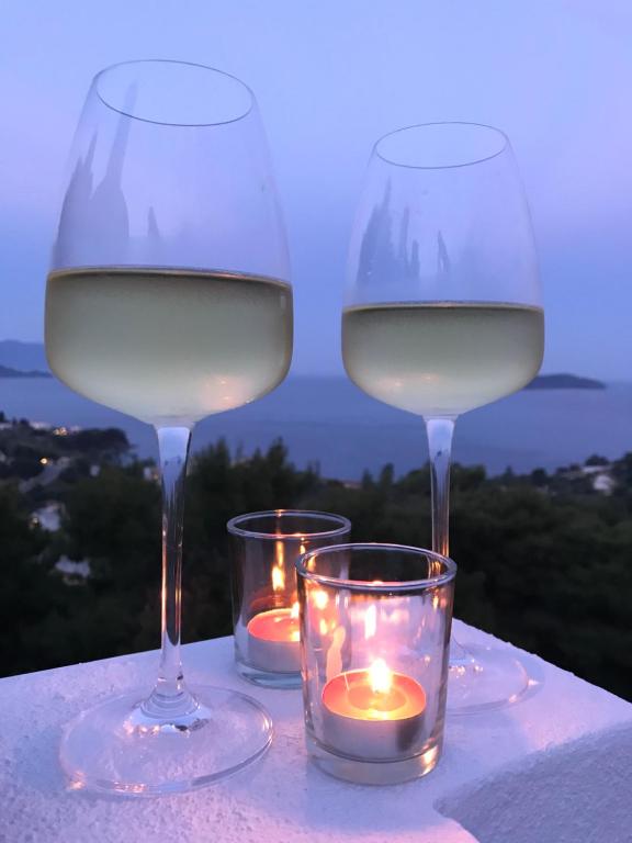 zwei Gläser Weißwein und Kerzen auf dem Tisch in der Unterkunft Andreas Village in Vassilias