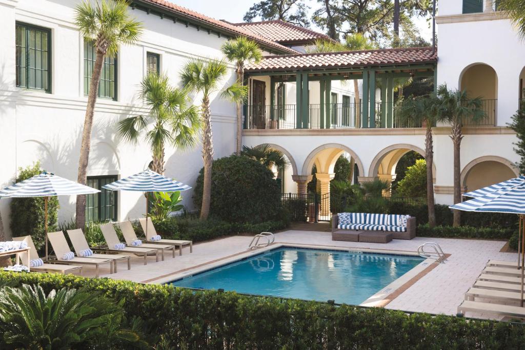 an exterior view of a house with a swimming pool and palm trees at The Inn by Sea Island in Saint Simons Island