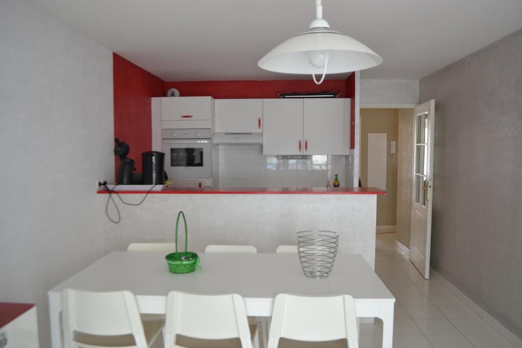 a kitchen with a white table and white cabinets at Vie de famille in Sainte-Cécile-Plage