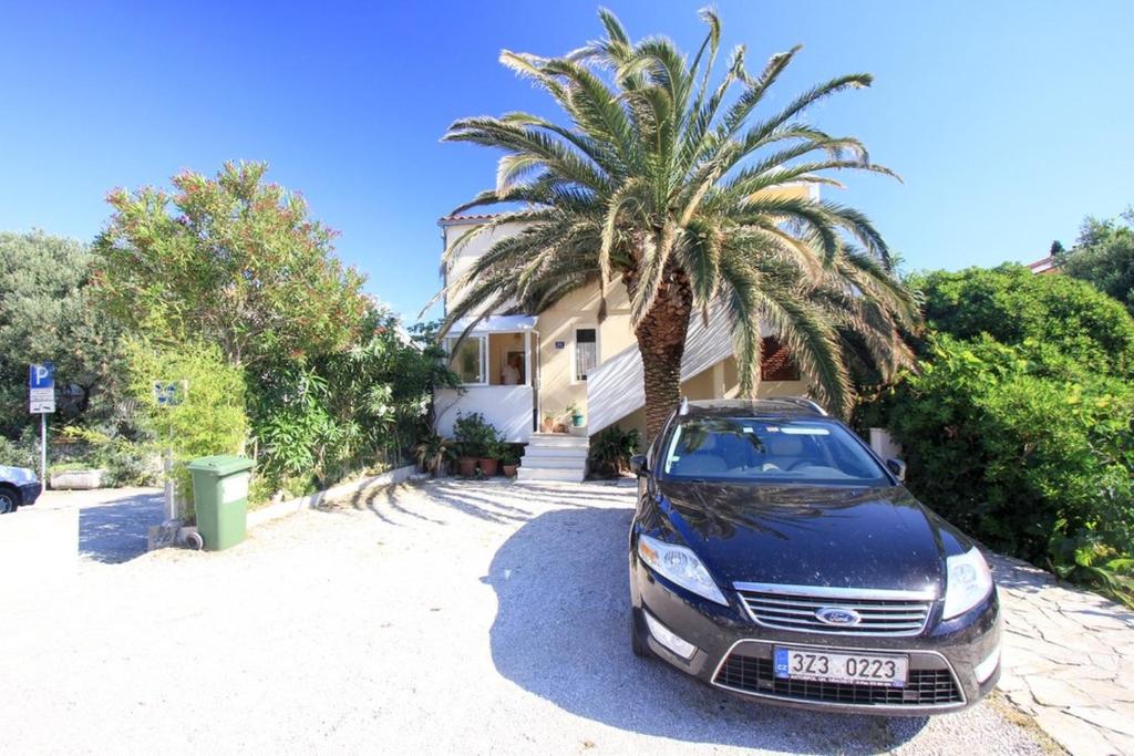 a car parked in front of a house with a palm tree at Apartments Garden in Orebić