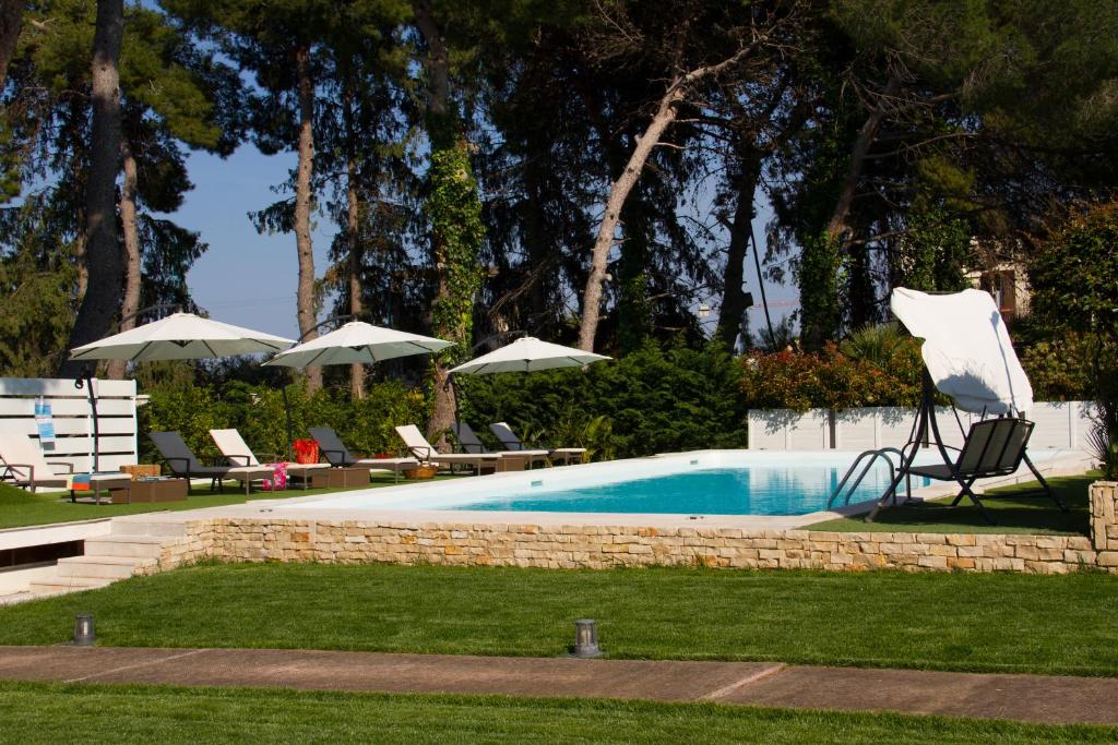 una piscina con sedie e ombrelloni in un cortile di Le Duchesse a Trani