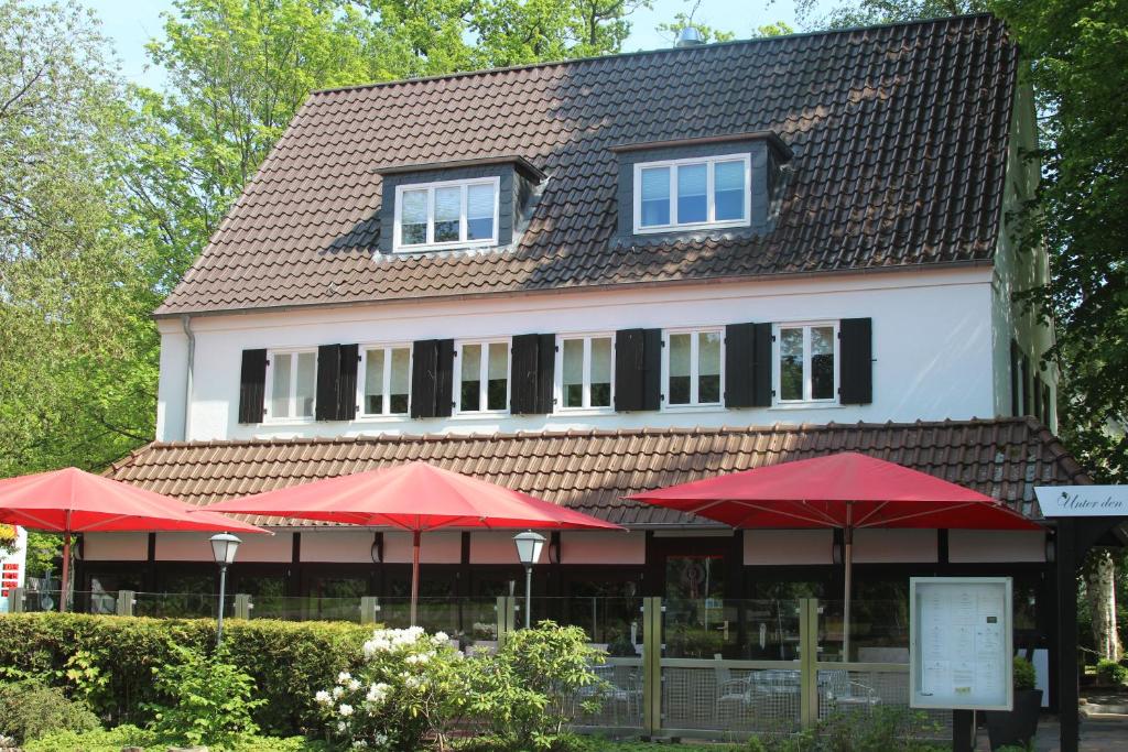 ein Gebäude mit roten Sonnenschirmen davor in der Unterkunft Hotel und Restaurant Zeus in Wolfsburg