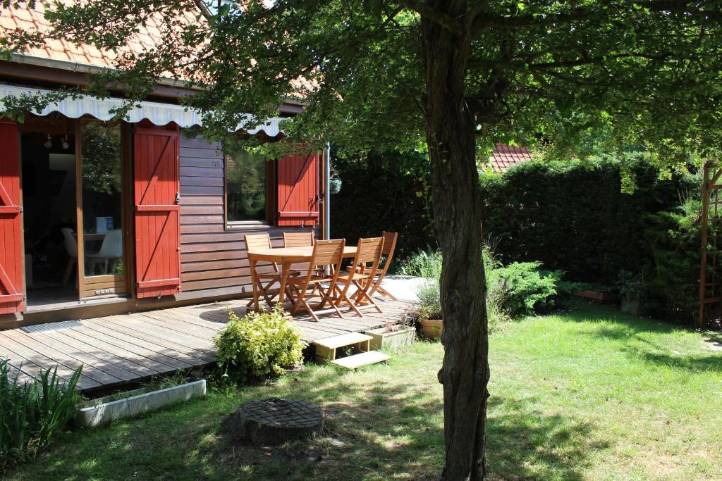 a wooden deck with a table and chairs next to a house at Chalet calme et cosy entre terre et mer in Berck-sur-Mer