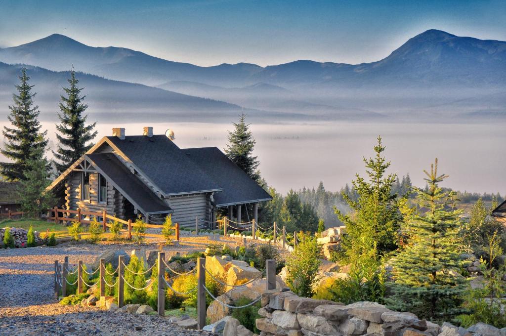 a log cabin in the mountains with fog in front of it at Charlton Estate in Yablunytsya