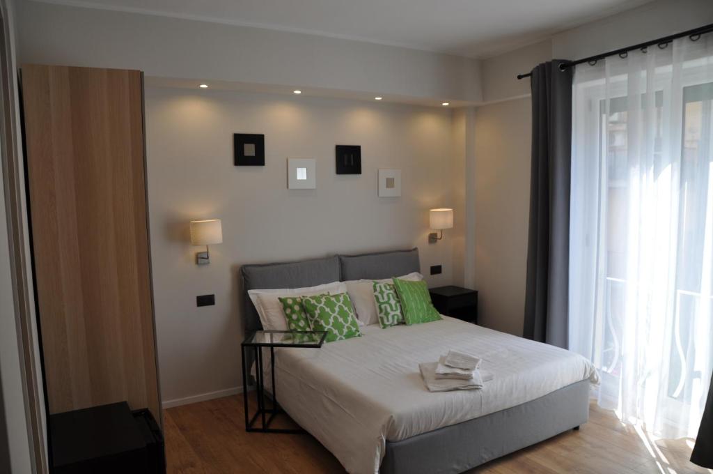 a bedroom with a bed with green pillows and a window at EVA LUXURY ROOMS CAGLIARI in Cagliari