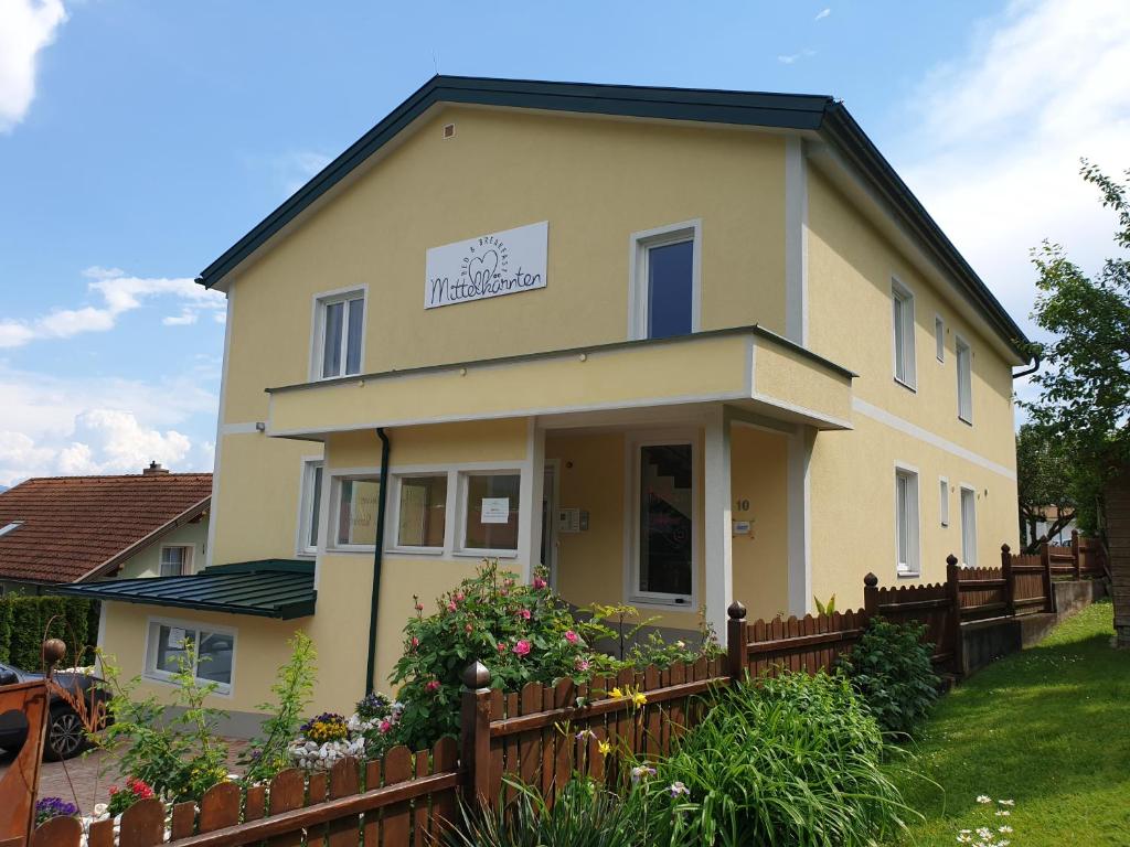 ein gelbes Haus mit einem Zaun davor in der Unterkunft Bed and Breakfast Mittelkärnten in Althofen