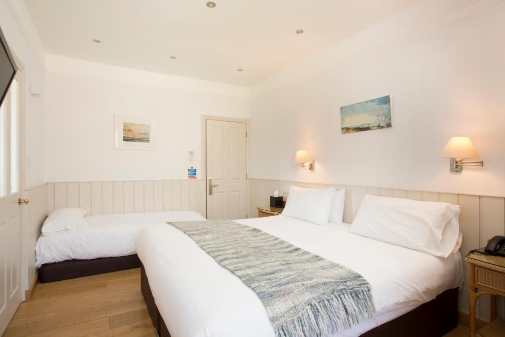 two beds in a room with white walls at Hotel Continental in Whitstable