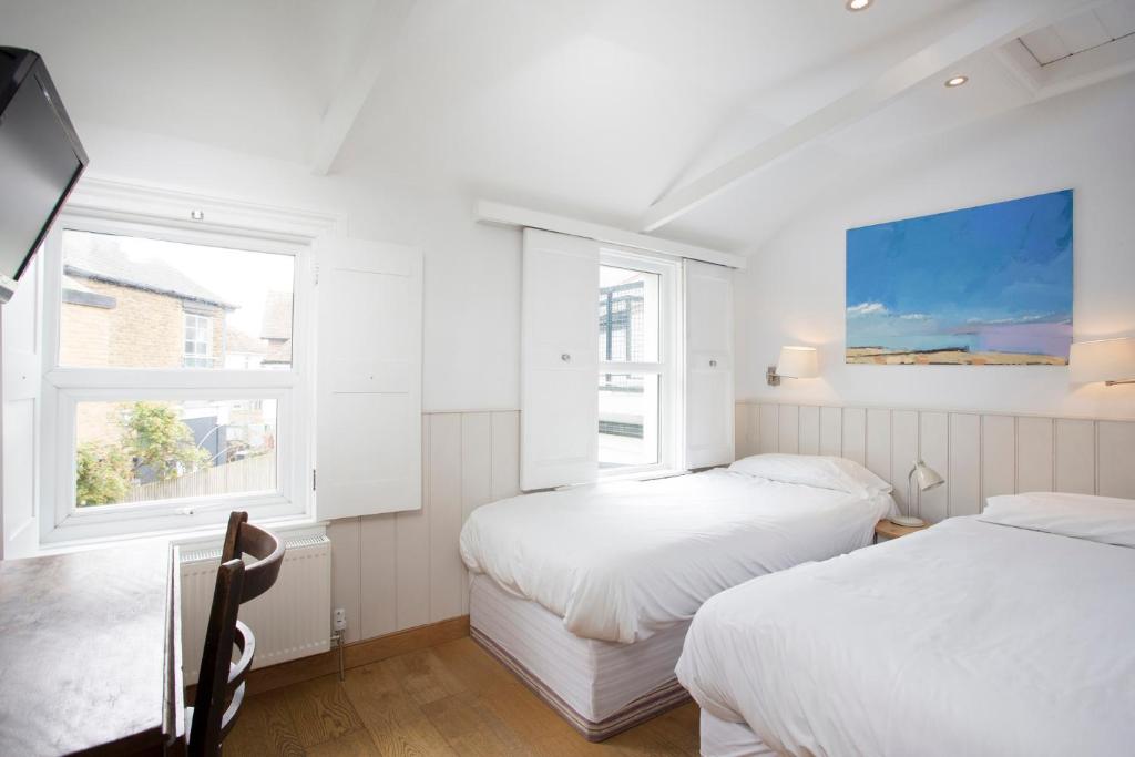 two beds in a white room with two windows at Hotel Continental in Whitstable