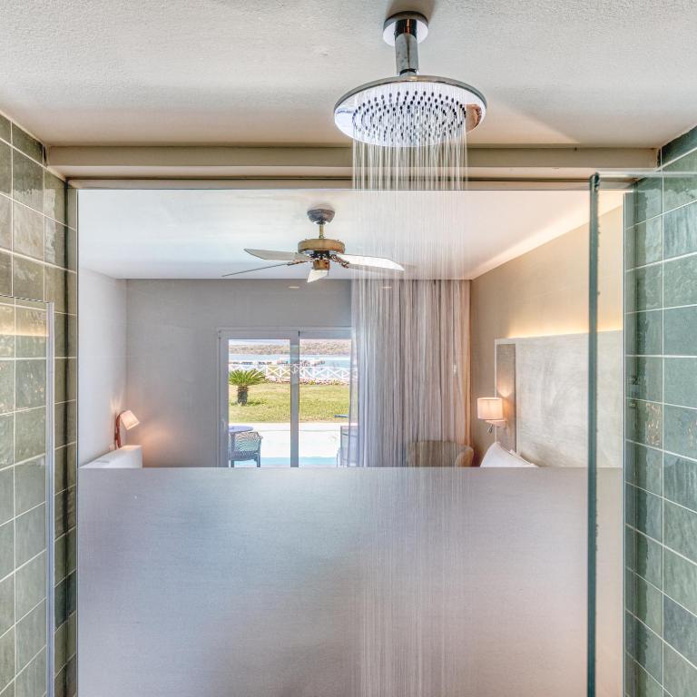 Bathroom with rainfall showerhead, green tile walls, and view to bedroom.