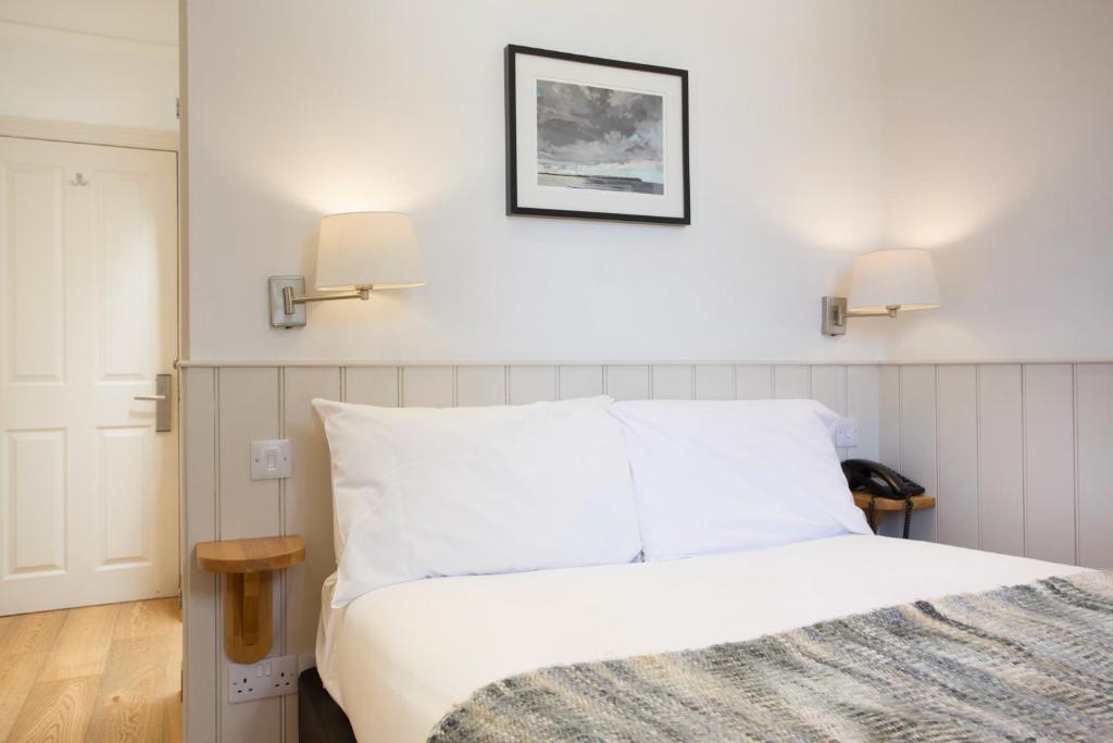 a bedroom with a white bed with two lights on the wall at Hotel Continental in Whitstable