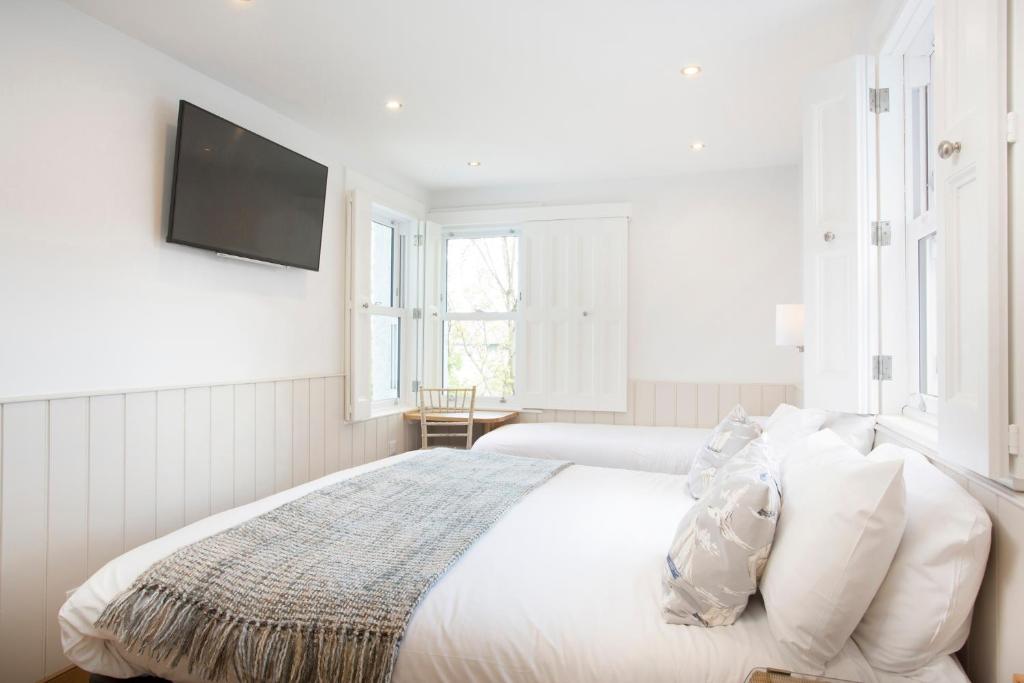 a white bedroom with a bed and a flat screen tv at Hotel Continental in Whitstable