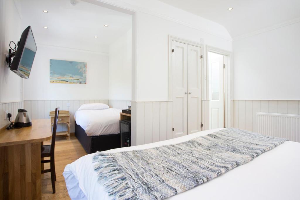 a white bedroom with a bed and a desk and a desk at Hotel Continental in Whitstable