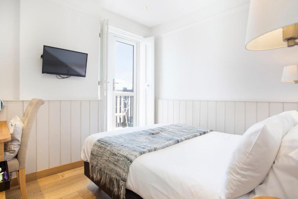 a white bedroom with a bed and a window at Hotel Continental in Whitstable