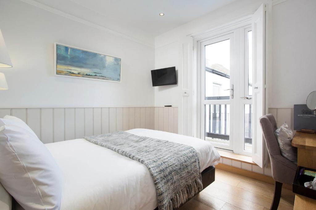 a white bedroom with a bed and a window at Hotel Continental in Whitstable