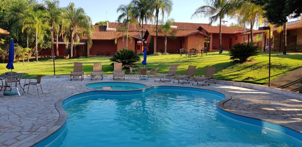 uma piscina com cadeiras e uma mesa num quintal em Pousada Beco da Lua em Olímpia