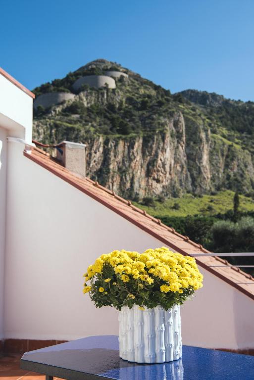 a vase with yellow flowers on a table with a mountain at Il Giardino di Venere in Mondello