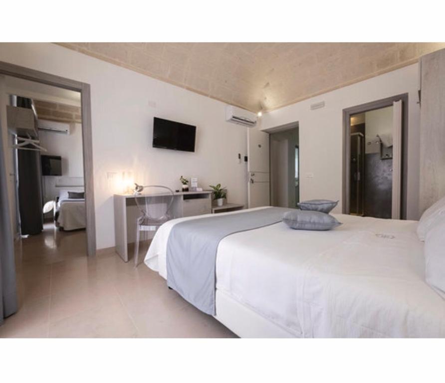 1 dormitorio con 1 cama blanca grande y escritorio en Imera B&B, en Favignana