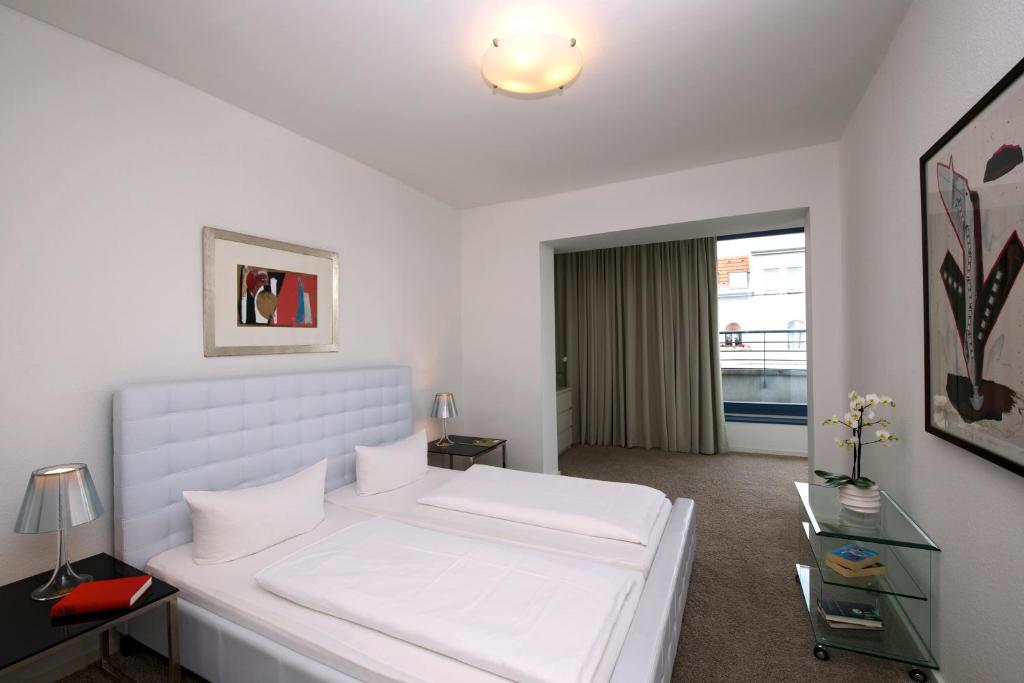 ein weißes Schlafzimmer mit einem großen weißen Bett und einem Fenster in der Unterkunft Art'Appart Suiten - kontaktloser Check-In in Berlin