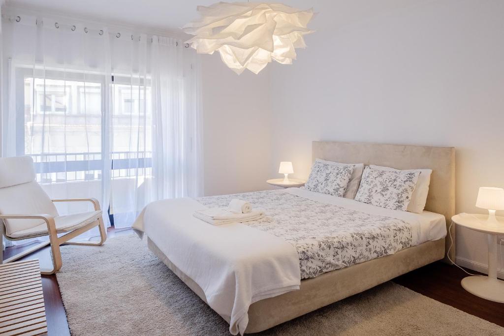 a white bedroom with a bed and a chandelier at Music House 3 bedroom Apt w garage in Porto