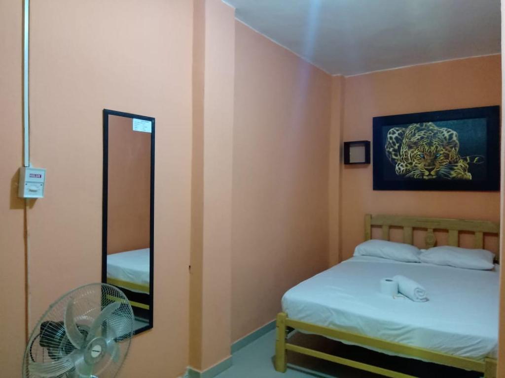 Habitación con cama, espejo y ventilador. en Hospedaje Las Palmeras, en Piura