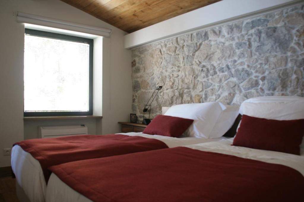 a bedroom with two beds and a stone wall at Quinta Vale da Roca in Sintra