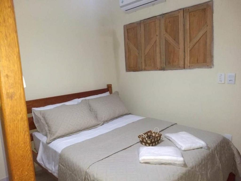 a bedroom with a bed with towels and a basket on it at Pousada Rio Sagi in Baía Formosa
