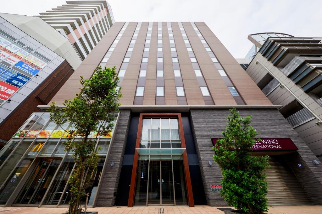 a tall building with trees in front of it at Hotel Wing International Kobe - Shinnagata Ekimae in Kobe