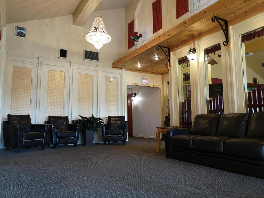 een lobby met banken en stoelen en een kroonluchter bij Hotellerie Jardins de Ville in Sherbrooke