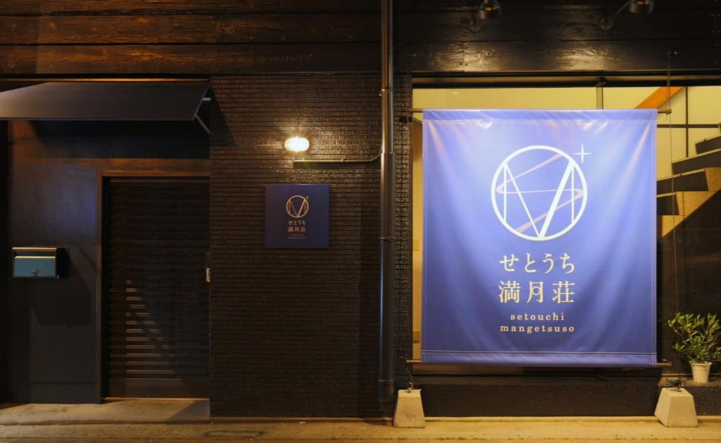 ein Banner auf der Seite eines Gebäudes mit einem Schild in der Unterkunft Setouchi Mangetsuso in Takamatsu