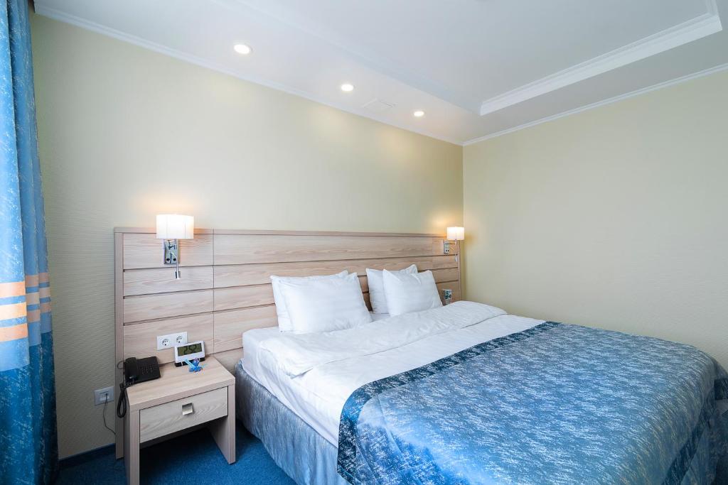 a hotel room with a bed with a blue blanket at Equator Congress Hotel in Vladivostok