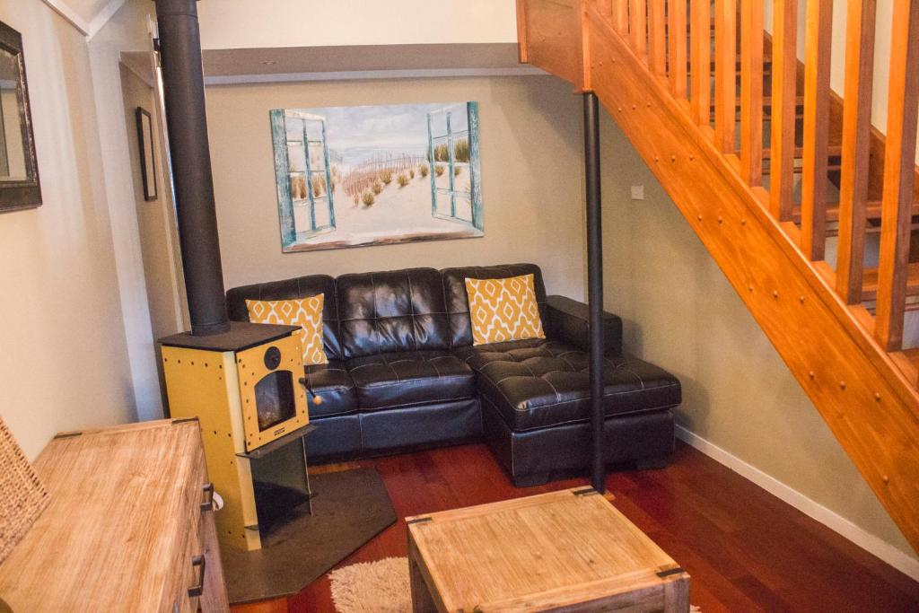 a living room with a leather couch and a staircase at Titore Lodge in Russell
