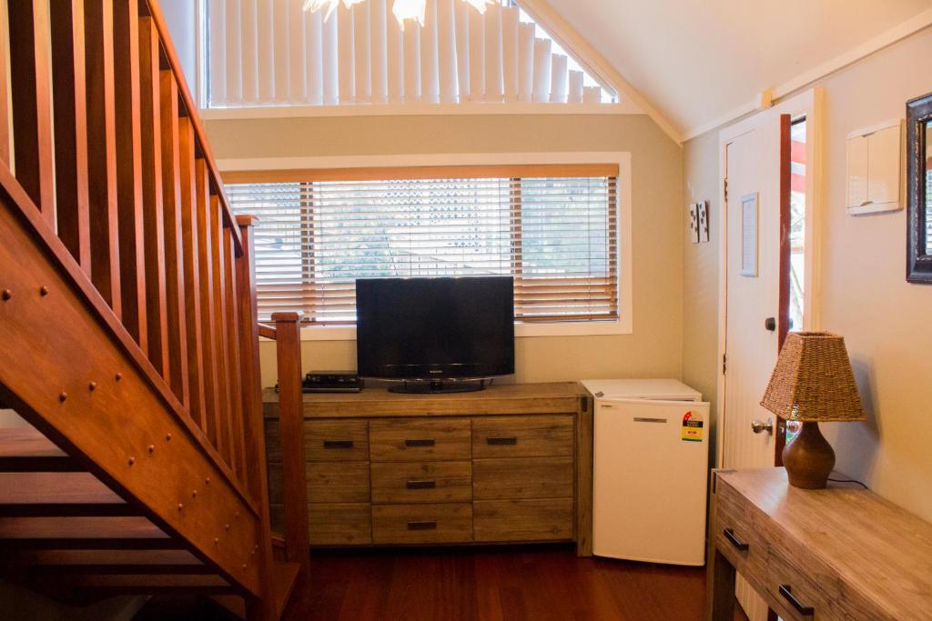 a room with a television on a dresser with a staircase at Titore Lodge in Russell
