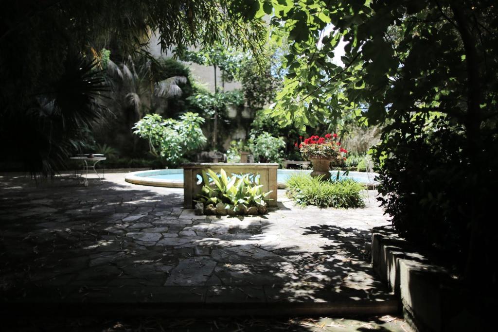 a shady garden with a bench and a fountain at Garden Suite at Palazzo Famularo in Lecce