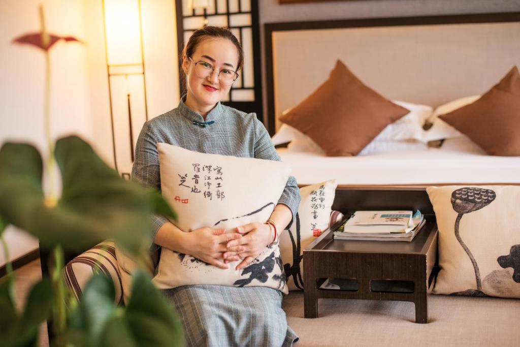 Una donna che tiene un pezzo di carta in una stanza d'albergo di Peach Blossom Resort Hotel a Guilin