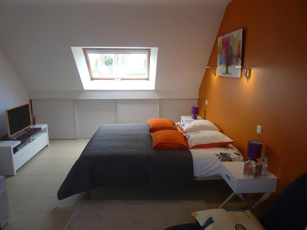 a bedroom with a bed with orange pillows and a window at Auprès de mon arbre in Saint-Gildas-de-Rhuys